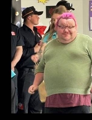A person with pink hair and glasses

Description automatically generated